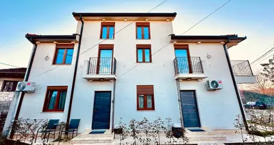 a white building with red windows and balconies at Central Station Apartments in Podgorica