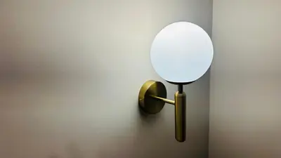 a mirror on a wall with a gold holder at Central Station Apartments in Podgorica
