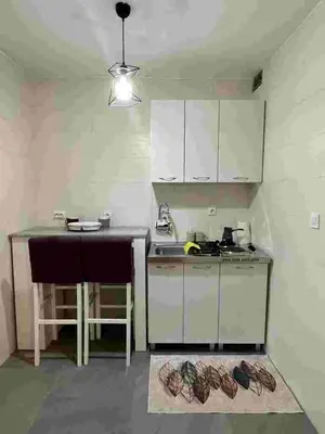 a small kitchen with white cabinets and a table at Sivas Bar in Bar