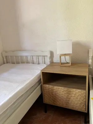 a bed next to a nightstand with a lamp on it at Apartman Pod lozom in Sutomore