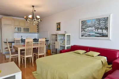 a bedroom with a red bed and a dining room at Central lux apt with garage in Budva
