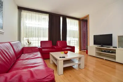 a living room with a red couch and a table at Central lux apt with garage in Budva