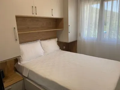 a bedroom with a large white bed with a window at Greystone House Apartments in Kovači