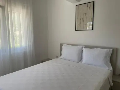 a bed with white sheets and a mirror on the wall at Greystone House Apartments in Kovači