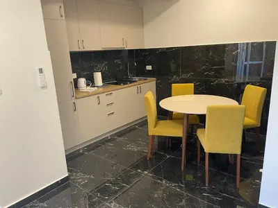 a kitchen with a table and yellow chairs at Greystone House Apartments in Kovači