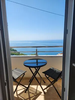 a balcony with a table and chairs and the ocean at Sunny Apartment in Prijevor