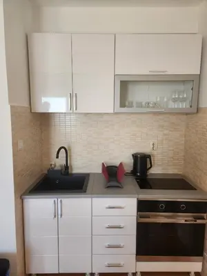 a kitchen with white cabinets and a sink at Sunny Apartment in Prijevor