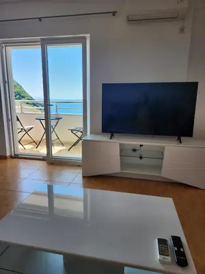 a living room with a tv and a view of the beach at Sunny Apartment in Prijevor