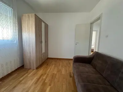 a living room with a couch and a wooden floor at Modern 2BR - Smart TV and WiFi in Podgorica