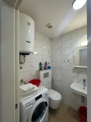 a bathroom with a washing machine and a toilet at Modern 2BR - Smart TV and WiFi in Podgorica