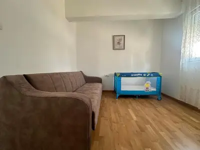 a living room with a couch and a toy crib at Modern 2BR - Smart TV and WiFi in Podgorica