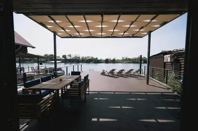a patio with a table and chairs next to a body of water at Casa Rio in Ulcinj