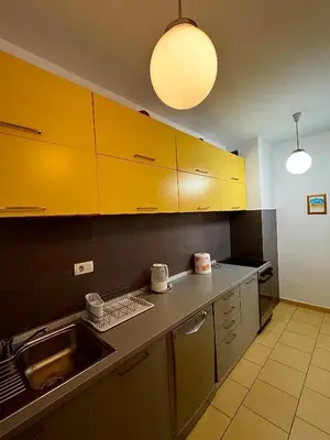 a kitchen with yellow cabinets and a sink at Top-Top 2 in Podgorica