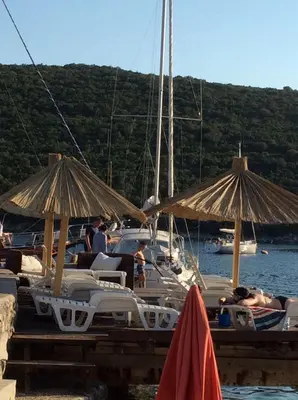 a group of chairs and umbrellas at a dock with boats at Apartment Bigovo in Tivat