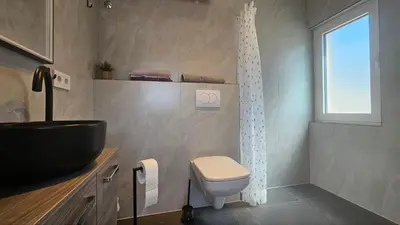 a bathroom with a sink and a toilet and a window at Panorama Suite in Dobra Voda