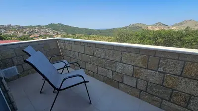 a blue chair sitting on a balcony with a brick wall at Panorama Suite in Dobra Voda