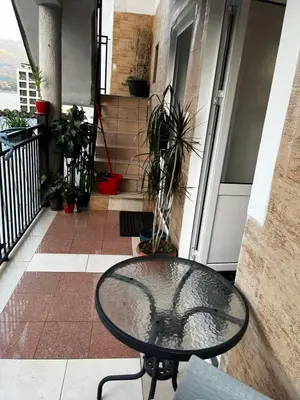 a glass table in front of a building with a balcony at Krsto in Budva
