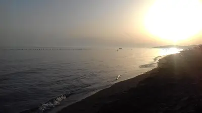 a beach with the sun setting over the water at Apartment Vuk i Novak in Ulcinj