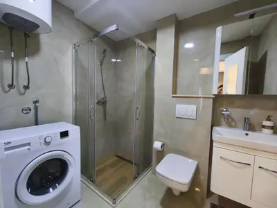 a bathroom with a shower and a washing machine at Sea & Sand Apartment in Bar