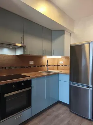 a kitchen with blue cabinets and a stainless steel refrigerator at Sea & Sand Apartment in Bar