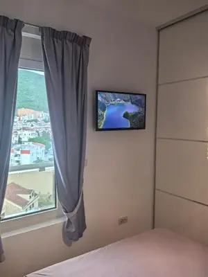 a bedroom with a window with a tv on the wall at City View 7 - Budva Center in Budva