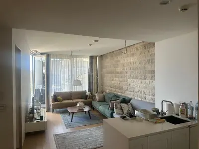 a living room with a green couch and a brick wall at Dukley Residence Budva Old Town in Budva
