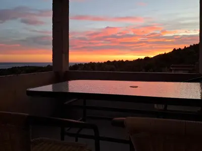 a table and chairs on a balcony with a sunset at Apartmani Šćekić in Bar