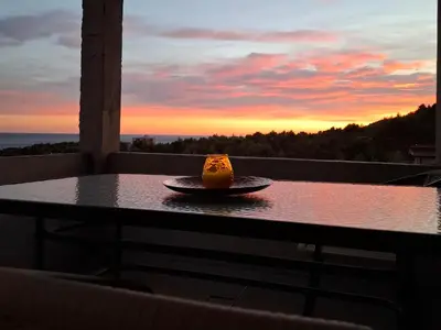 a piece of cake on a plate on a table with a sunset at Apartmani Šćekić in Bar