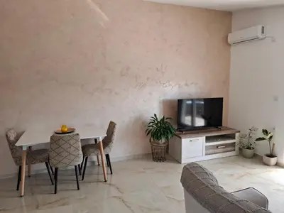 a living room with a table and a tv at Apartmani Šćekić in Bar