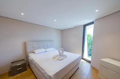 a white bedroom with a bed with a towel on it at Villa Patria in Budva