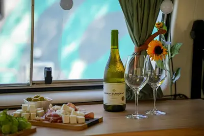 a bottle of wine next to a plate of cheese and wine glasses at Camperlife Montenegro in Podgorica