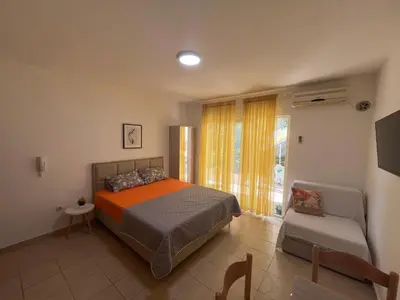 a bedroom with a bed and a chair and a window at Apartment Sara in Petrovac na Moru