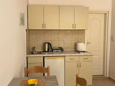 a small kitchen with white cabinets and a table at Apartment Sara in Petrovac na Moru