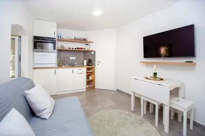 a living room with a bed and a desk and a kitchen at Charming Apartment in The Old Town in Budva