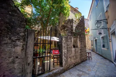 an alley with an iron gate with a table and chairs at Charming Apartment in The Old Town in Budva