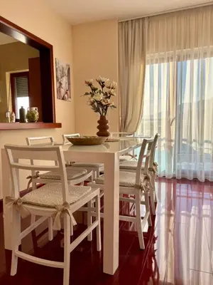 a white dining room table with chairs and a vase with flowers at Mia Bella in Bar