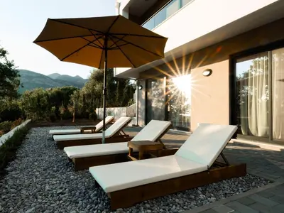 a row of lounge chairs and an umbrella on a patio at Villa Amara -Luxury Villa with Private Pool & Hot Tub in Bar