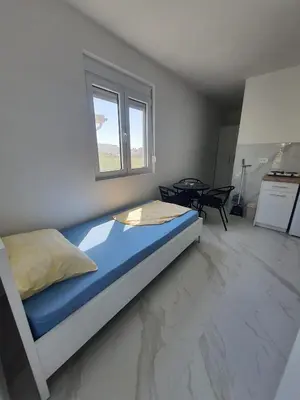 a bedroom with a bed and a window at Apartmani Ajla in Donji Štoj