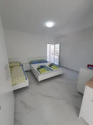 two beds in a room with white walls and marble floors at Apartmani Ajla in Donji Štoj