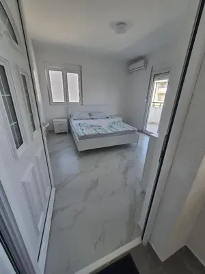 an empty room with a bed and a door at Apartmani Ajla in Donji Štoj
