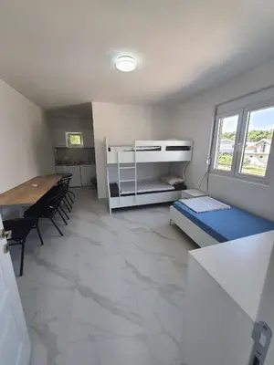 a room with a desk and a bed and a table at Apartmani Ajla in Donji Štoj