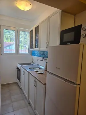 a kitchen with white cabinets and a white refrigerator at Тишина и покой в Будве in Kravlja