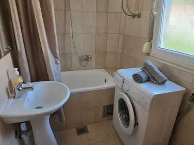 a bathroom with a washing machine and a sink at Тишина и покой в Будве in Kravlja