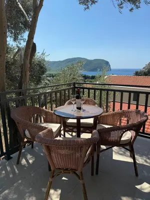 a table and chairs on a balcony with a bottle of wine at Apartmani Krsto in Kravlja