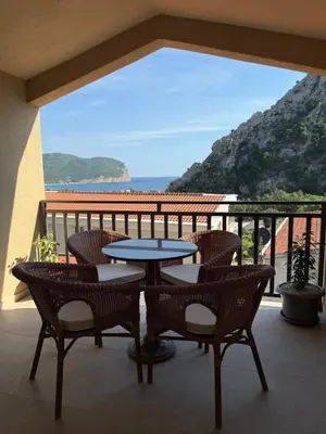 a table and chairs on a balcony with a view of the ocean at Apartmani Krsto in Kravlja