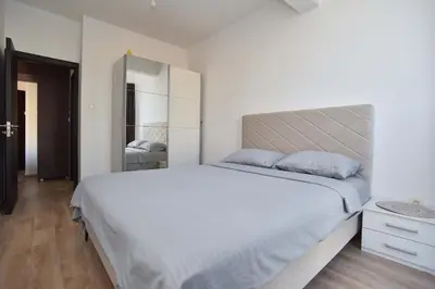 a white bedroom with a large bed and a mirror at Omega 4 Apartment in Budva