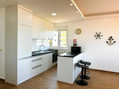 a kitchen with white cabinets and a sink and a stool at GlamSea in Bar