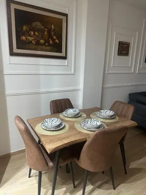 a dining room table with four chairs and a painting at Lux apartman sa garažom in Budva