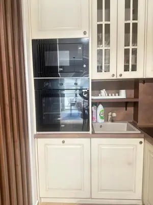 a kitchen with white cabinets and a black microwave at Lux apartman sa garažom in Budva