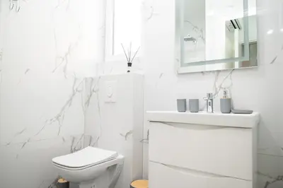 a white bathroom with a toilet and a sink at Amarea Apartments in Ulcinj